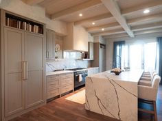 a large kitchen with marble counter tops and white cabinetry, along with wooden floors