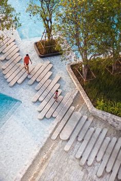 two people are walking up and down the stairs next to an empty swimming pool in a park