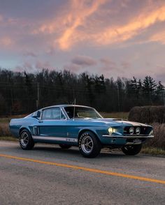 an old mustang car is parked on the side of the road