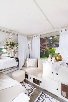 the inside of a camper with white curtains and furniture