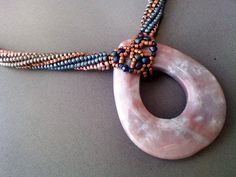 a beaded necklace with an oval shaped object on it's end, sitting on a table