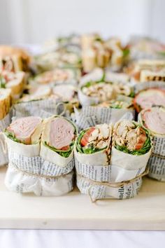 sandwiches wrapped in newspaper sitting on top of a table