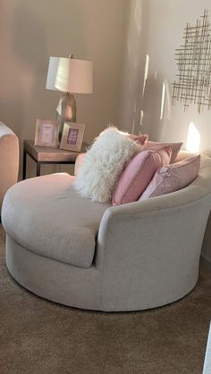 a living room filled with furniture and pillows on top of a chair next to a lamp