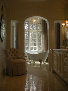 a large bathroom with a tub and chandelier in the corner, along with an arched doorway that leads to another room