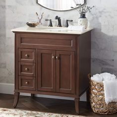 a bathroom vanity with a mirror above it and a basket on the floor next to it