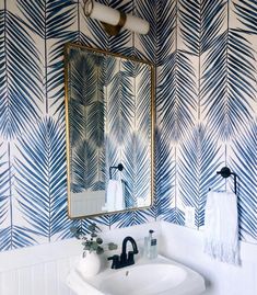 a white sink sitting under a bathroom mirror next to a wall mounted faucet