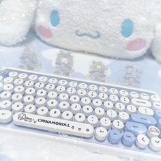 a close up of a keyboard with a stuffed animal in the background