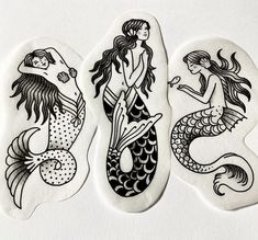 three stickers depicting mermaids on white paper