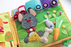 a close up of an open book with felt animals and buttons on the front cover