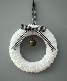 a white wreath hanging on the wall with a black and white checkered ribbon around it