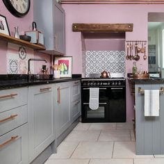 a kitchen with pink walls and grey cabinets