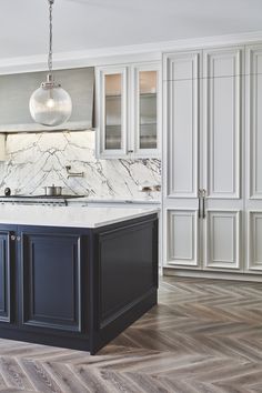 a kitchen with an island and marble counter tops in the center, surrounded by white cabinets