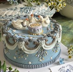 a blue and white cake sitting on top of a table next to some flower vases