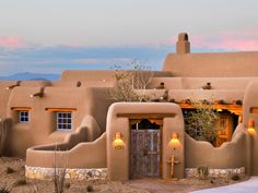 an adobe - style house in the desert at sunset