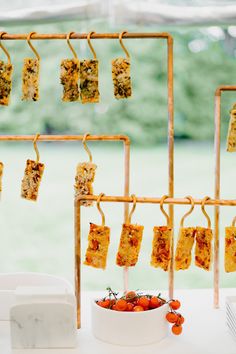 some food is hanging up on the rack next to a bowl of tomatoes and carrots