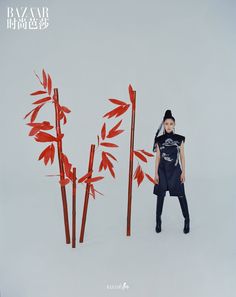 a woman standing in front of two tall red sticks with arrows sticking out of them