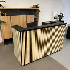 an office reception area with black counter and wooden paneling on the front, along with two planters