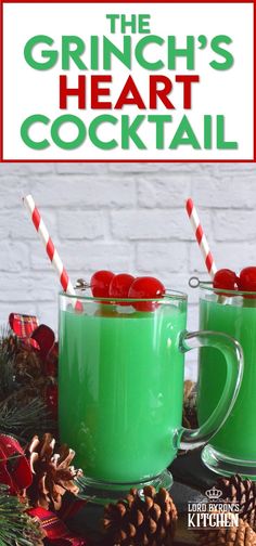 two mugs filled with green liquid and topped with candy canes, surrounded by pine cones