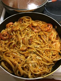 a pan filled with pasta and shrimp on top of a stove