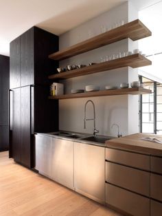 a kitchen with stainless steel appliances and open shelving on the wall above the sink