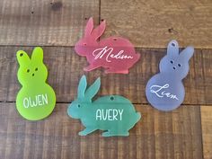 four different colored plastic easter bunnies sitting on top of a wooden floor