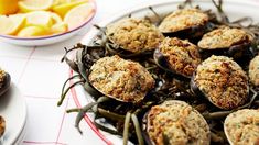 a plate full of cooked mussels with lemon wedges on the side next to it