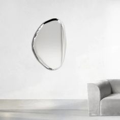 a white couch sitting in front of a mirror on the wall next to a chair