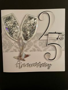 a 25th anniversary card with two wine glasses on it and the number twenty five in silver