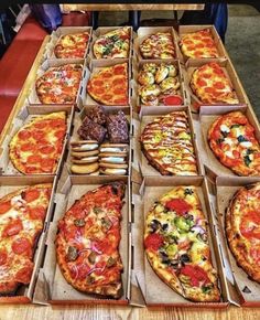 many different types of pizza in boxes on a table