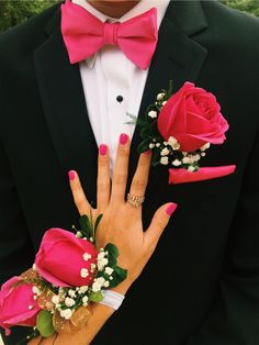 a man in a tuxedo with pink flowers on his fingers and two roses attached to his wrist