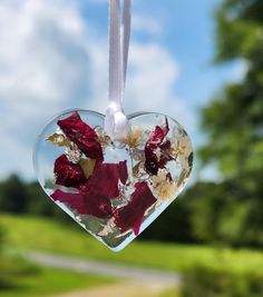 a heart shaped ornament with dried flowers hanging from it's side on a string