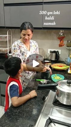 a woman helping a child prepare food in the kitchen