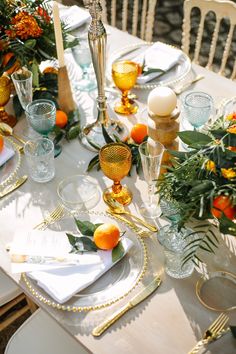 the table is set with oranges and gold place settings