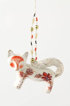 an ornament shaped like a fox hanging from a chain on a white background