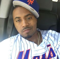 a man sitting in the back seat of a car wearing a new york mets baseball uniform