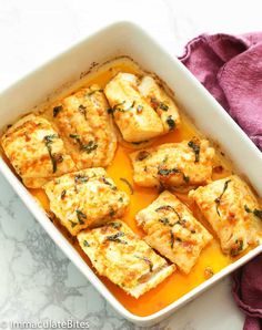 chicken and cheese casserole in a white dish on a marble counter top next to a pink towel