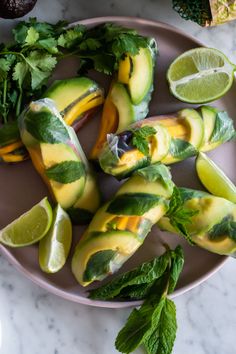 sliced avocados on a plate with limes, cilantro and mint