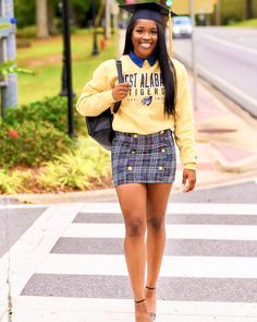 a woman in a yellow shirt and plaid skirt is crossing the street