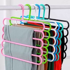 a rack with several different colored pants hanging from it's sides and two pairs of socks on the other side