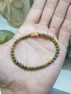 "Mini Unakite beads and a solid 9 Karat Gold (Au375) Piyao / Pixiu charm in this luckycharmed beaded bracelet 😍😊. The gold Pixiu is custom-made and used over 2 grams of solid 9 Karat Gold for better resistance against pressure and impact; made to last long 😃. Giftable luckycharm bracelet; Good Luck, Prosperity and Good Fortune.  Glossy, green and pink toned Unakite beads (5 mm bead size). Pixiu is 1.3 cm length and weighs 2.3 grams more or less. Bracelet size is set at 17 cm but in case it needs downsizing or resizing (up to 20 cm) just let us know after payment by messaging us at \"Message Seller\" under the listing title. Bracelet also comes with extra sets of elastic strings, a wire guide and 5 pcs of spare Unakite beads (on top of size 17 cm or the upsize requested)." Good Luck Jewelry With Round Natural Stone Beads, Traditional Beaded Bracelets For Good Luck, Spiritual Beaded Bracelets With Natural Stones For Good Luck, Good Luck Gemstone Beaded Bracelets, Green Beaded Bracelets For Good Luck, Traditional Hand-strung Beaded Bracelets For Good Luck, Spiritual Jade Beaded Bracelets With Polished Beads, Lucky Charm Bracelet, Jade Bangle