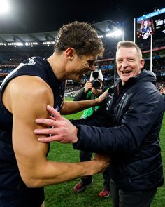 an image of a man being hugged by another man on the field at a football game