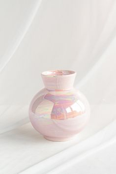 a pink vase sitting on top of a white sheet