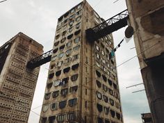 two tall buildings with windows and balconies on the top one is made of concrete