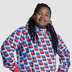 a woman with dreadlocks standing in front of a white background wearing a colorful shirt