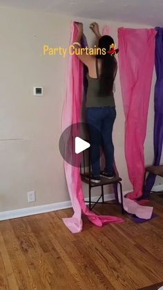 a woman standing on a chair in front of some pink and purple curtain's