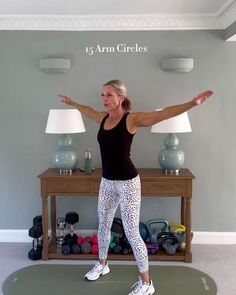 a woman standing on a yoga mat with her arms spread out in front of her