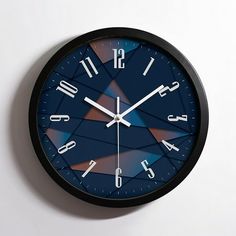 a black clock with blue and red designs on it's face against a white wall