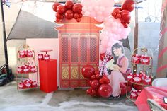 a red and white party with balloons, decorations and gifts on the floor in front of a chinese building