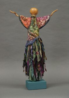 a sculpture of a woman with her arms spread out in the air, wearing a colorful dress