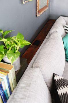 a living room with a couch and books on the table next to it is decorated with green plants